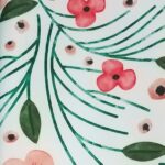 Peach, coral, and green floral print polyester dinner napkin on a white background.