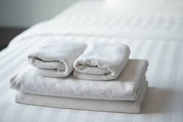 Folded white towels on the hotel bed, feels cozy - Premier Linen Co.